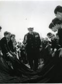 Fotografia de Américo Tomás caminhando sobre capas de trajes universitários, por ocasião da visita efetuada às Piscinas de Évora