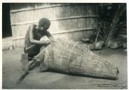 Fotografia de um indígena fazendo uma nassa para pesca