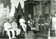 Fotografia de Américo Tomás, acompanhado por militares e por uma figura eclesiástica, assistindo a uma cerimónia no interior de uma igreja 