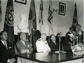 Fotografia de Américo Tomás, acompanhado por José Augusto da Costa Almeida e por António Augusto Peixoto Correia, ouvindo discursos durante uma cerimónia oficial, por ocasião da visita de estado efetuada a Moçambique