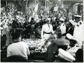 Fotografia de Américo Tomás saudando a população no interior da viatura oficial na cidade de Chimoio, durante a visita de estado efetuada a Moçambique