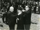 Fotografia de Américo Tomás, acompanhado por José Henrique de Azeredo Perdigão, impondo as insígnias da comenda da Ordem de Cristo a Rita Sirvarte Essayan, por ocasião da cerimónia de inauguração da estátua de Calouste Gulbenkian