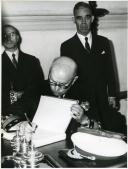 Fotografia de Américo Tomás, acompanhado por Eduardo de Arantes e Oliveira, assinando o livro de honra, por ocasião da inauguração da Pousada dos Loios em Évora