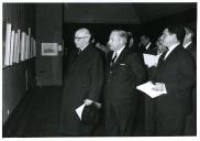 Fotografia de Américo Tomás acompanhado por César Moreira Batista nas instalações do Secretariado Nacional de Informação, presidindo à inauguração de uma exposição da autoria de José Rodrigues