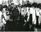 Fotografia de Américo Tomás caminhado sobre batinas de estudantes universitárias durante a visita efetuada ao Alentejo de 12 a 14 de abril