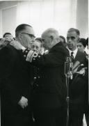 Fotografia de Américo Tomás, acompanhado por Eduardo de Arantes e Oliveira, nas Caldas da Rainha, condecorando Leonel Sottomayor por ocasião da visita efetuada ao distrito de Leiria