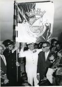 Fotografia de Américo Tomás acompanhado por António Augusto Peixoto em Maxixe, segurando no estandarte da vila por ocasião da visita de estado efetuada a Moçambique