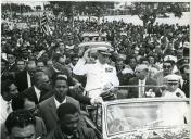 Fotografia de Américo Tomás, acompanhado por António Augusto Peixoto, em Inhambane, seguindo em cortejo automóvel por ocasião da visita de estado efetuada a Moçambique