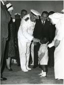 Fotografia de Américo Tomás, acompanhado por Gertrudes Rodrigues Tomás, em Xai-Xai, cumprimentando uma criança por ocasião da visita de estado efetuada a Moçambique