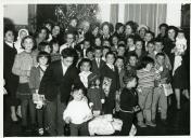 Fotografia de Américo Tomás, acompanhado por Gertrudes Rodrigues Tomás, Maria Natália Rodrigues Tomás e por Maria Madalena Rodrigues Tomás, rodeados de crianças, durante as celebrações natalícias no Palácio de Belém