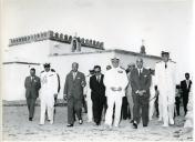 Fotografia de Américo Tomás, acompanhado por António Augusto Peixoto Correia e por César Moreira Batista, caminhando junto de uma igreja na Ilha de Moçambique por ocasião da visita de estado efetuada a Moçambique