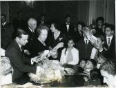 Fotografia de Américo Tomás, acompanhado por Gertrudes Rodrigues Tomás, oferecendo brinquedos e guloseimas a crianças oriundas de famílias numerosas, no Palácio de Belém