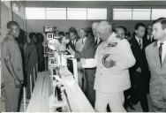 Fotografia de Américo Tomás, acompanhado por António Augusto Peixoto Correia, inaugurando o Centro o Emissor de Mulenvos em Luanda, por ocasião de uma paragem de três dias em Angola, durante o regresso da visita de estado efetuada a Moçambique