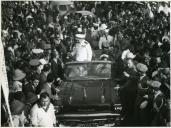 Fotografia de Américo Tomás saudando a população no interior da viatura oficial na cidade de Tete, durante a visita de estado efetuada a Moçambique