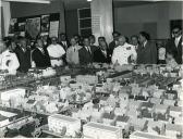 Fotografia de Américo Tomás acompanhado por António Augusto Peixoto Correia na cidade de Maputo observando uma maqueta para a construção de um bairro social, por ocasião da visita de estado efetuada a Moçambique