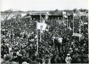 Fotografia de Américo Tomás, acompanhado por António Augusto Peixoto, desfilando no meio de uma multidão de pessoas em Xai-Xai, por ocasião da visita de estado efetuada a Moçambique