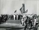 Fotografia de Américo Tomás, acompanhado por Gertrudes Rodrigues Tomás e por António Augusto Peixoto Correia, assistindo ao desfile da guarda de honra após o desembarque em Lourenço Marques, por ocasião da visita de estado efetuada a Moçambique