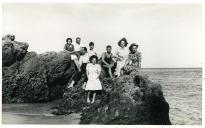 Fotografia de Maria Natália e Maria Madalena, filhas de Américo Tomás, com familiares e amigos sentados nas rochas junto à Praia de Alpertuche na Arrábida, em Setúbal